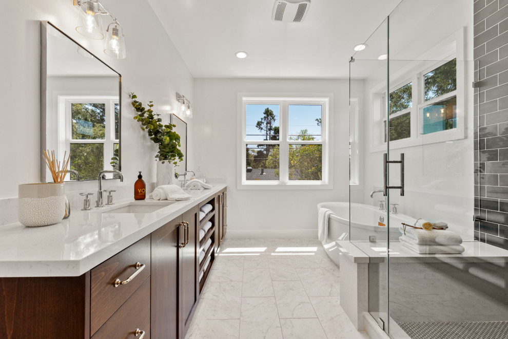Country master bathroom in San Francisco with a hinged shower door, a double vanity, a built-in vanity, a freestanding tub, shaker cabinets, dark wood cabinets, a corner shower, gray tile, an undermount sink, white floor, white benchtops and a shower seat.