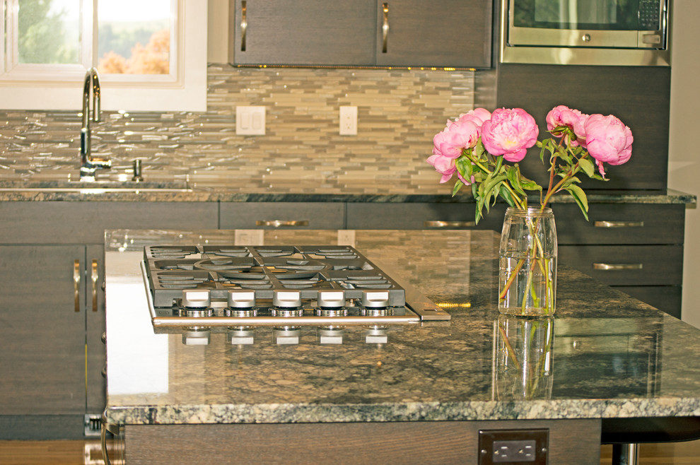 Eat-in kitchen - large transitional l-shaped light wood floor eat-in kitchen idea in Seattle with an undermount sink, flat-panel cabinets, dark wood cabinets, granite countertops, green backsplash, glass tile backsplash, stainless steel appliances and an island
