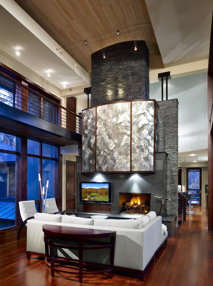 This is an example of a large contemporary open concept living room in Other with a standard fireplace, a wall-mounted tv, beige walls, medium hardwood floors and a tile fireplace surround.