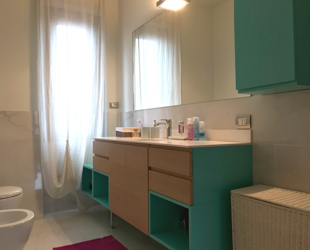 Inspiration for a medium sized contemporary ensuite bathroom in Milan with turquoise cabinets, a built-in bath, white tiles, porcelain tiles, white walls, porcelain flooring, an integrated sink, solid surface worktops, white floors, white worktops, a single sink and a freestanding vanity unit.
