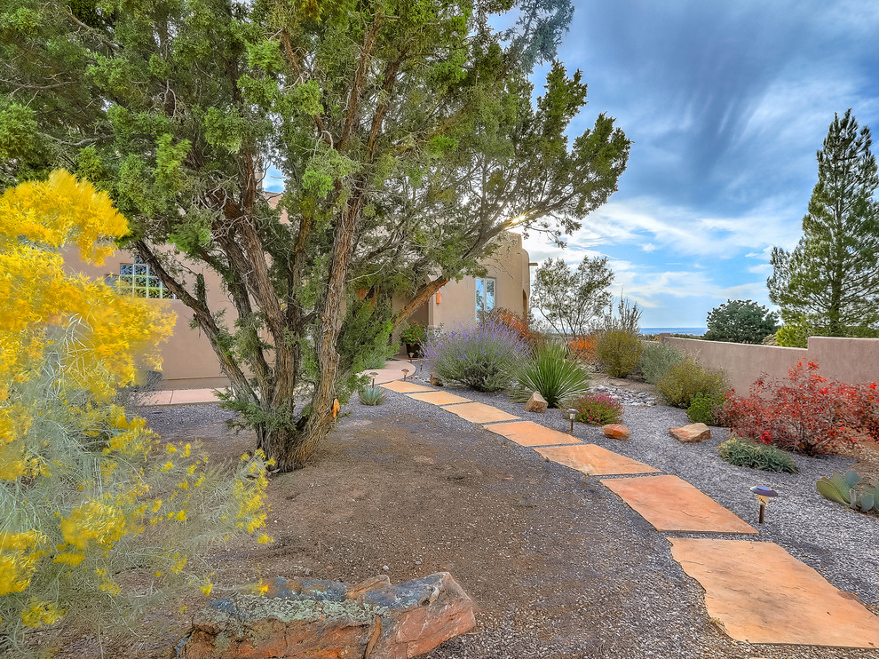 Photo of a mid-sized front yard full sun xeriscape for fall in Albuquerque with natural stone pavers.
