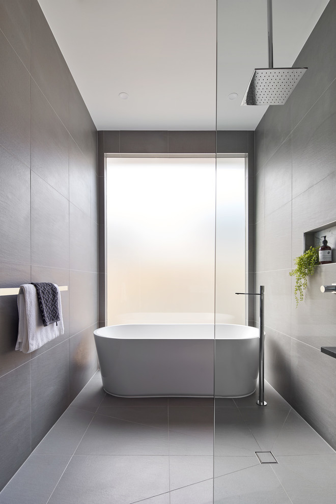 Design ideas for a mid-sized modern master bathroom in Melbourne with furniture-like cabinets, black cabinets, an open shower, a wall-mount toilet, gray tile, stone slab, white walls, a console sink, marble benchtops, grey floor, an open shower, white benchtops, a freestanding tub and porcelain floors.