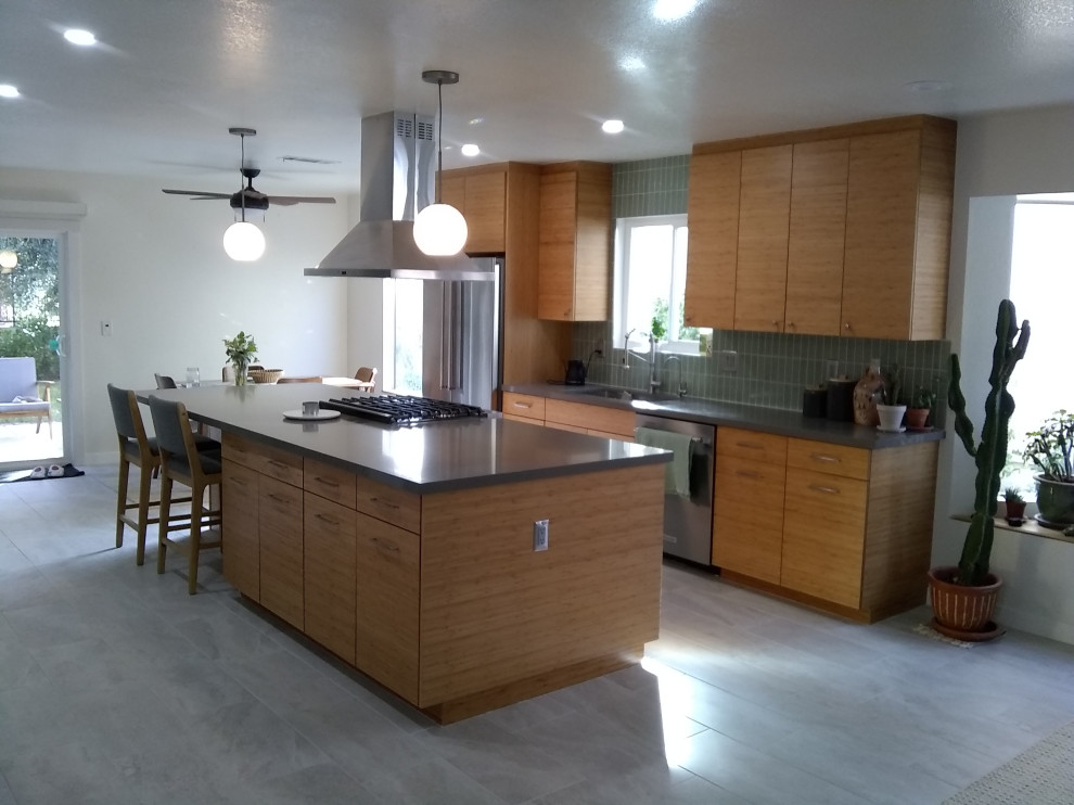 Réalisation d'une cuisine minimaliste en bois brun de taille moyenne avec un placard à porte plane, un plan de travail en quartz modifié, une crédence verte et un plan de travail gris.