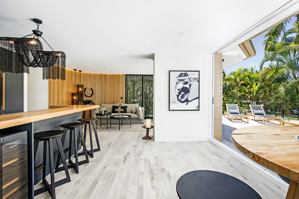 Small beach style single-wall open plan kitchen in Sunshine Coast with an undermount sink, flat-panel cabinets, grey cabinets, concrete benchtops, multi-coloured splashback, ceramic splashback, black appliances, ceramic floors, with island, grey floor and brown benchtop.