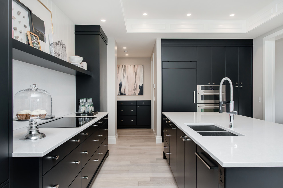 Example of a large trendy light wood floor kitchen design in Calgary with a double-bowl sink, flat-panel cabinets, black cabinets, quartz countertops, white backsplash, paneled appliances and an island