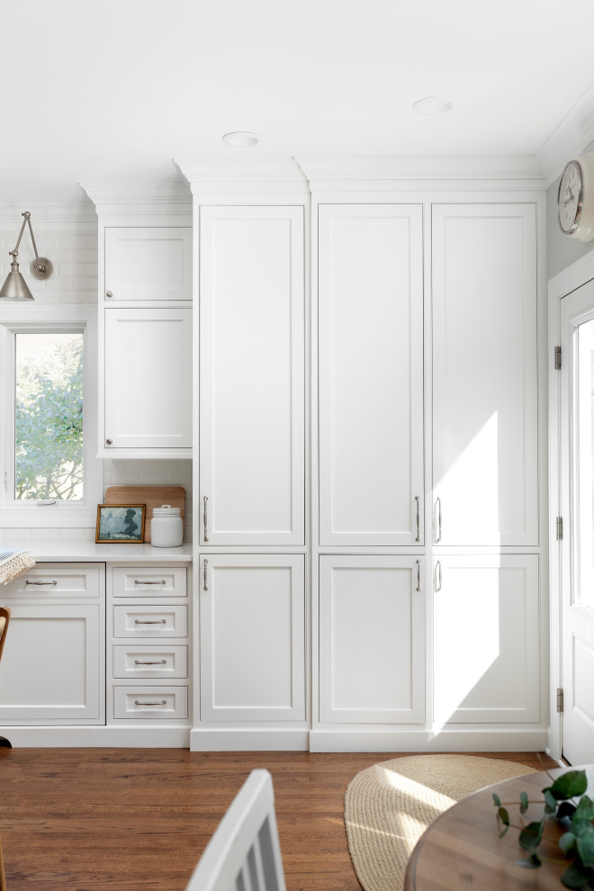 Exempel på ett mellanstort klassiskt vit vitt kök, med en rustik diskho, luckor med profilerade fronter, vita skåp, bänkskiva i kvarts, vitt stänkskydd, stänkskydd i keramik, integrerade vitvaror, mellanmörkt trägolv, en köksö och brunt golv