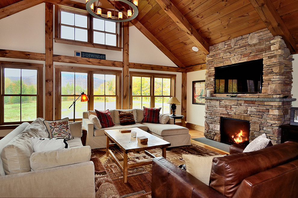 Photo of a large country living room in Burlington with medium hardwood floors, a standard fireplace and a wall-mounted tv.
