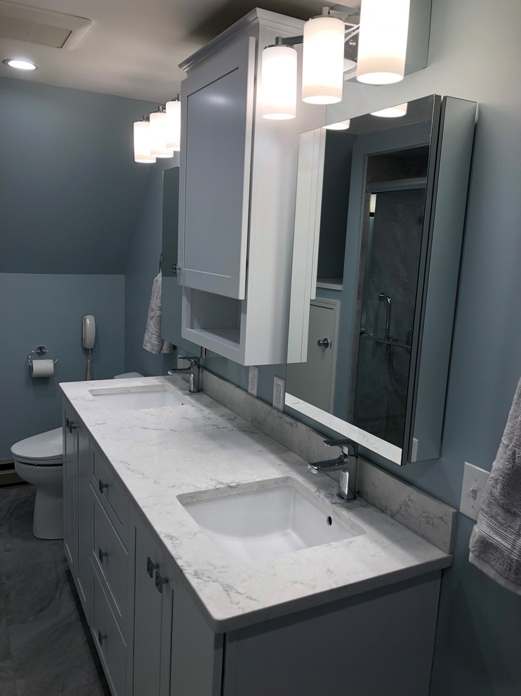 Mid-sized transitional master bathroom in Burlington with raised-panel cabinets, grey cabinets, a double shower, a bidet, gray tile, porcelain tile, blue walls, porcelain floors, an undermount sink, engineered quartz benchtops, grey floor, a sliding shower screen and white benchtops.