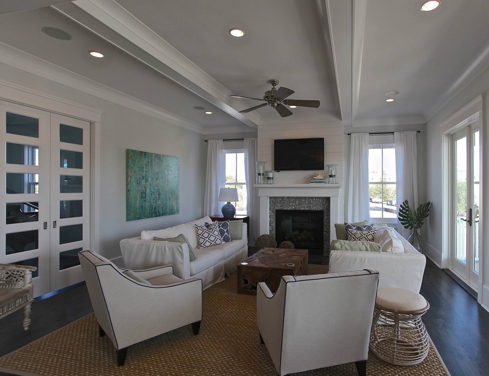 Mid-sized beach style open concept living room in Charleston with grey walls, dark hardwood floors, a standard fireplace, a tile fireplace surround, a wall-mounted tv and brown floor.