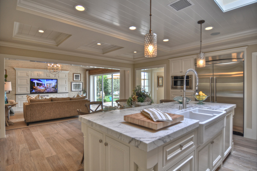 Open concept kitchen - beach style open concept kitchen idea in Los Angeles with stainless steel appliances, a double-bowl sink, marble countertops, recessed-panel cabinets and white cabinets
