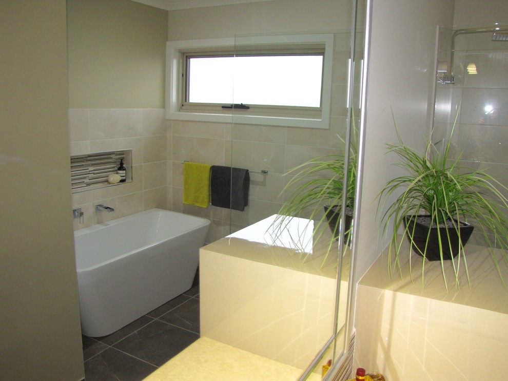 This is an example of a mid-sized contemporary bathroom in Melbourne with shaker cabinets, beige cabinets, a freestanding tub, an open shower, beige tile, ceramic tile, beige walls, ceramic floors, a drop-in sink and laminate benchtops.