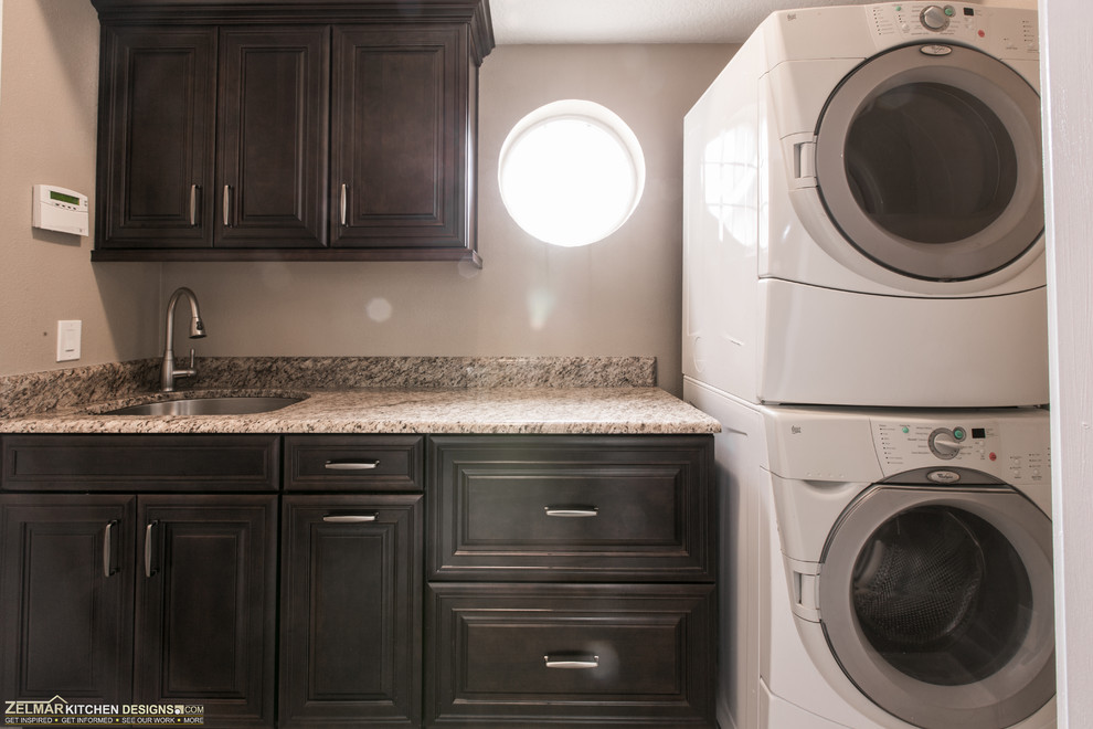 Photo of a mid-sized transitional u-shaped laundry room in Orlando with an undermount sink, raised-panel cabinets, dark wood cabinets and granite benchtops.