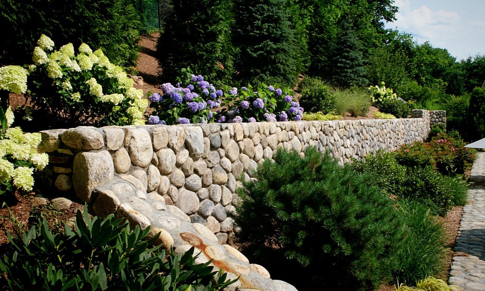 Inspiration for a mid-sized traditional backyard full sun formal garden for summer in New York with a retaining wall and natural stone pavers.