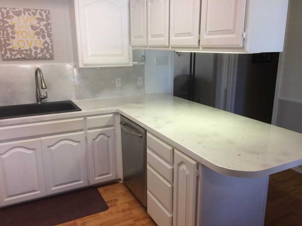 Enclosed kitchen - mid-sized transitional u-shaped dark wood floor and brown floor enclosed kitchen idea in Austin with a drop-in sink, raised-panel cabinets, white cabinets, quartz countertops, white backsplash, stone slab backsplash, stainless steel appliances and a peninsula