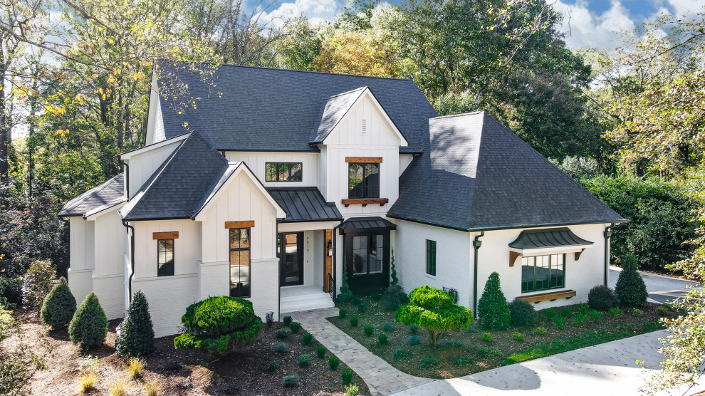 Großes, Zweistöckiges Landhausstil Einfamilienhaus mit gestrichenen Ziegeln, weißer Fassadenfarbe, Satteldach, Schindeldach, schwarzem Dach und Wandpaneelen in Charlotte