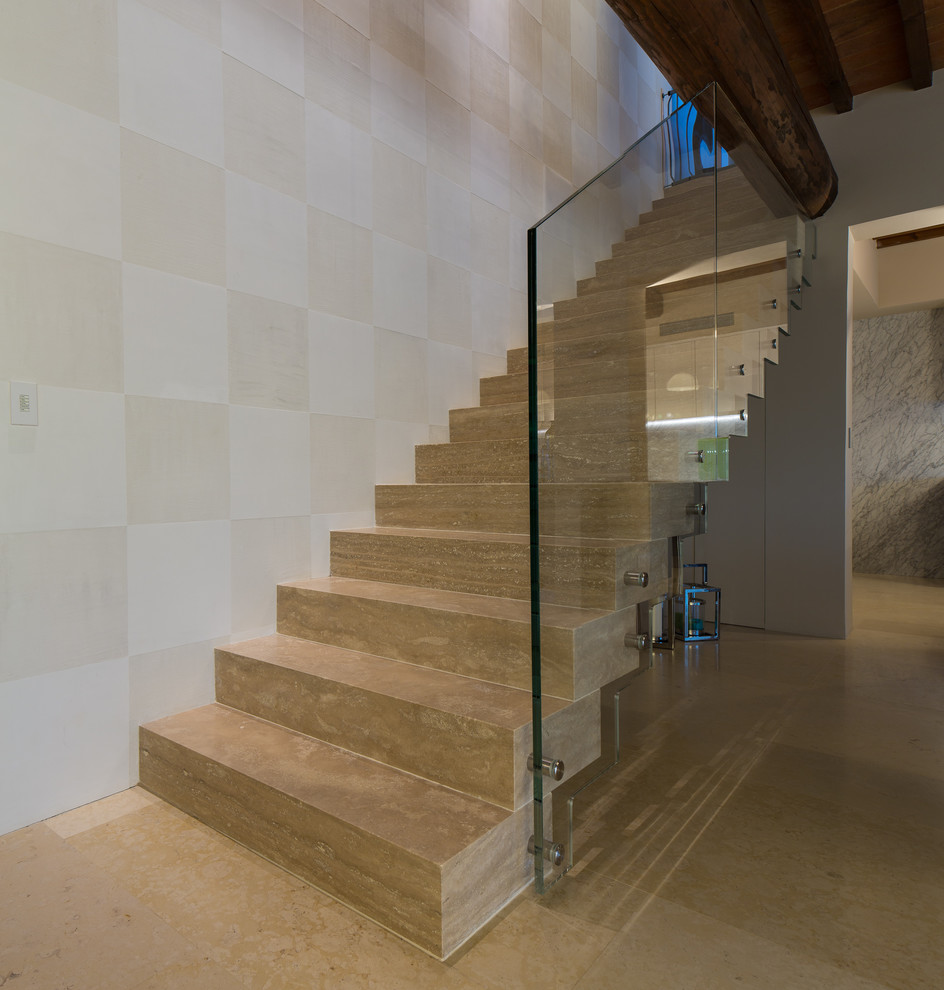 This is an example of a mid-sized country travertine floating staircase in Denver with travertine risers and glass railing.