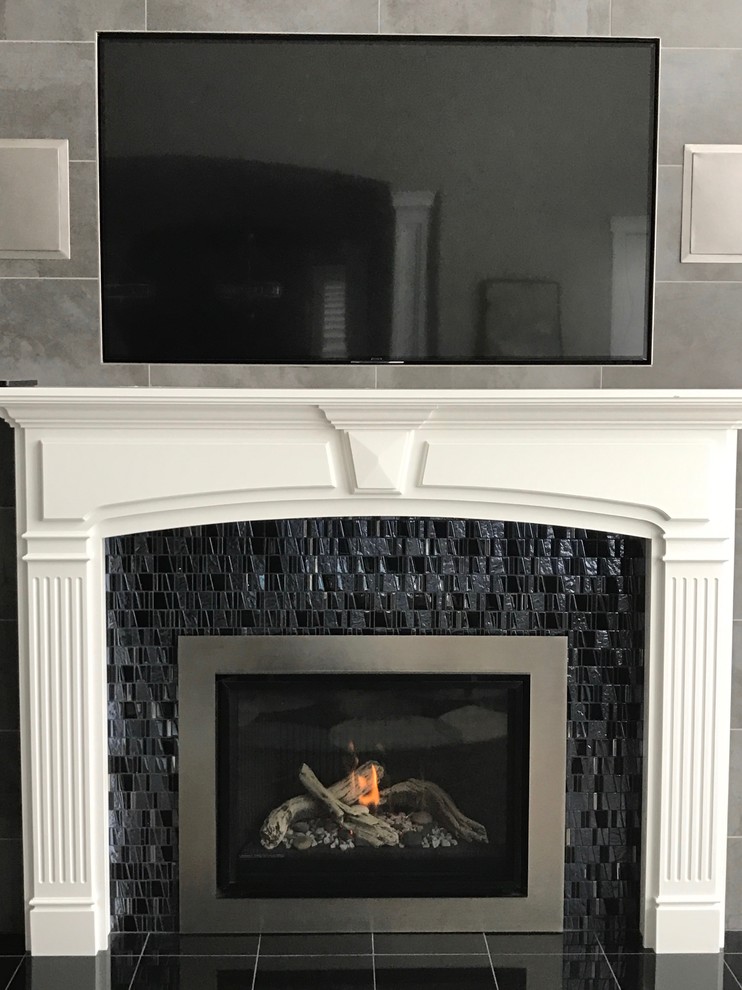 Photo of a mid-sized traditional formal enclosed living room in Salt Lake City with grey walls, porcelain floors, a standard fireplace, a tile fireplace surround, a wall-mounted tv and black floor.
