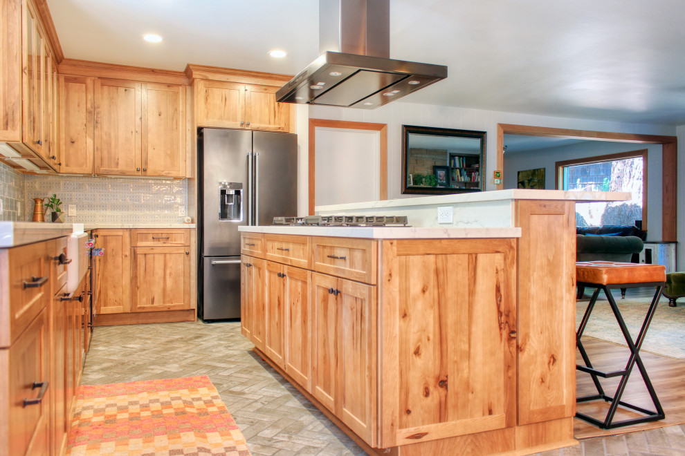 Mid-sized mountain style l-shaped brick floor and brown floor open concept kitchen photo with a farmhouse sink, shaker cabinets, medium tone wood cabinets, quartz countertops, blue backsplash, ceramic backsplash, stainless steel appliances, an island and white countertops