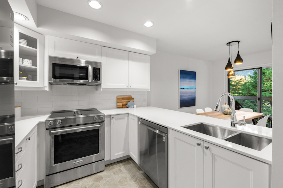 Kitchen - small transitional u-shaped laminate floor and gray floor kitchen idea with a double-bowl sink, shaker cabinets, white cabinets, quartz countertops, white backsplash, porcelain backsplash, stainless steel appliances and white countertops