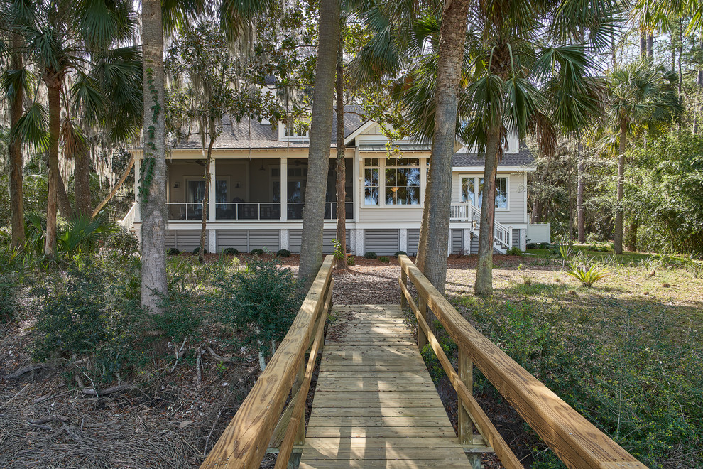 This is an example of a large beach style two-storey beige house exterior in Charleston with a shingle roof and wood siding.