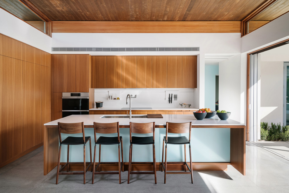 Inspiration for a contemporary open plan kitchen in Other with medium wood cabinets, solid surface benchtops, white splashback, with island and white benchtop.