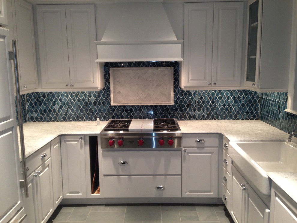 Inspiration for a mid-sized traditional u-shaped open plan kitchen in Seattle with a farmhouse sink, recessed-panel cabinets, yellow cabinets, blue splashback, glass tile splashback, stainless steel appliances and porcelain floors.