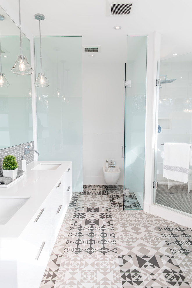Large contemporary master bathroom in Toronto with flat-panel cabinets, white cabinets, a freestanding tub, a corner shower, a wall-mount toilet, gray tile, porcelain tile, white walls, porcelain floors, an undermount sink and solid surface benchtops.