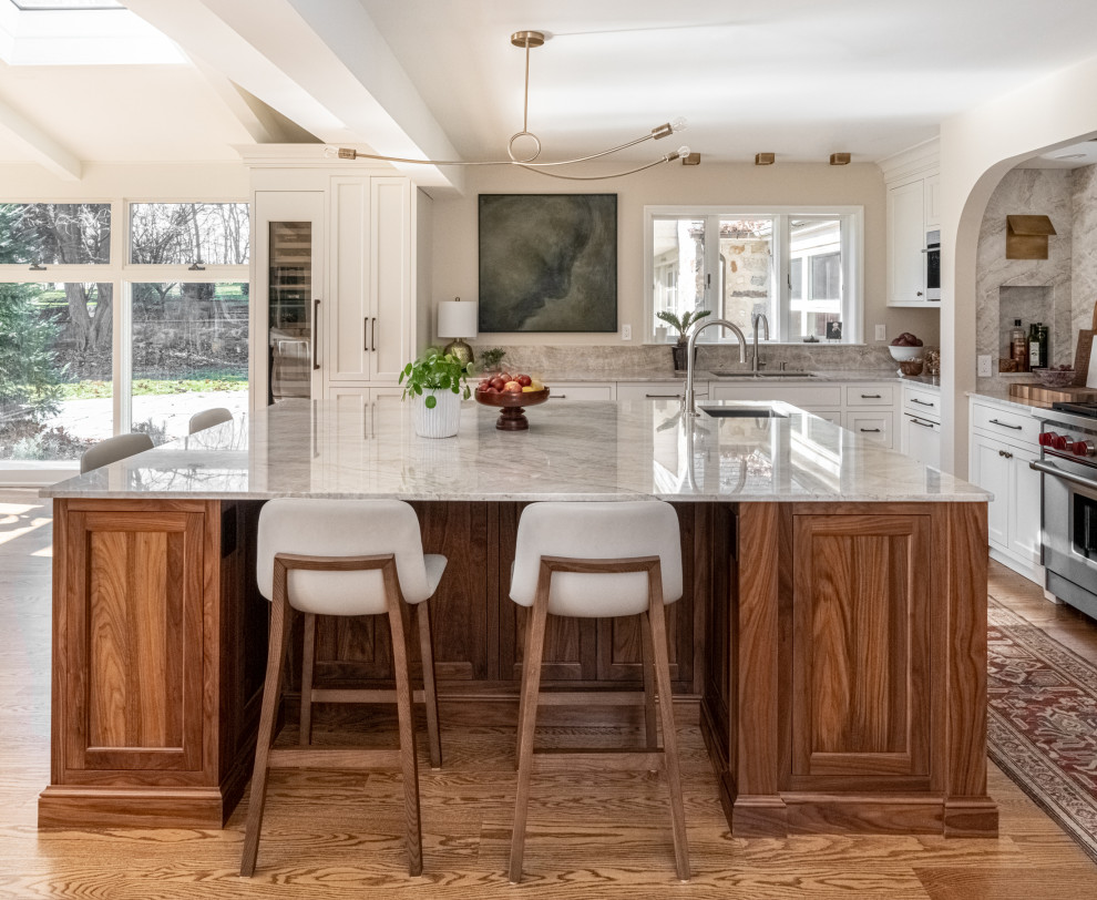 Idéer för att renovera ett stort vintage beige beige kök, med en undermonterad diskho, skåp i shakerstil, vita skåp, bänkskiva i kvartsit, beige stänkskydd, stänkskydd i sten, integrerade vitvaror, mellanmörkt trägolv, en köksö och brunt golv