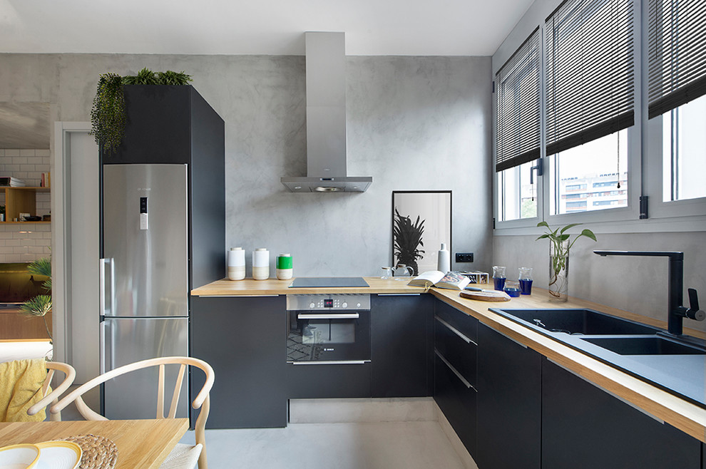 Design ideas for a contemporary l-shaped eat-in kitchen in Barcelona with flat-panel cabinets, wood benchtops, stainless steel appliances, a double-bowl sink, black cabinets, no island and grey floor.