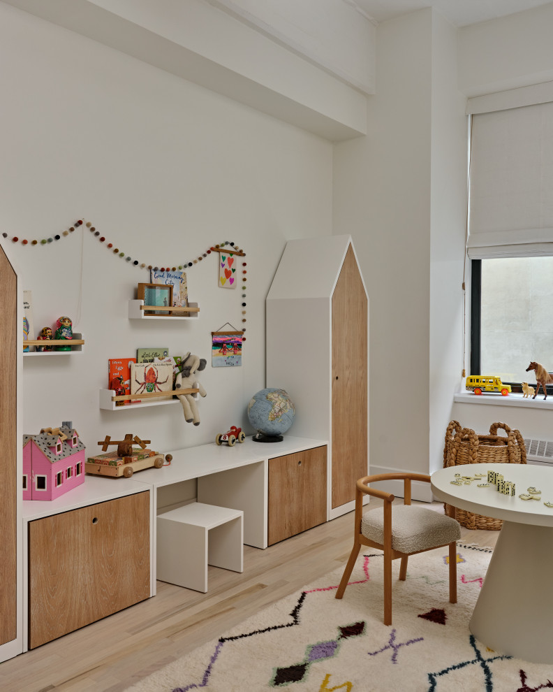 Photo of a contemporary kids' room for kids 4-10 years old in New York with white walls, light hardwood floors and beige floor.