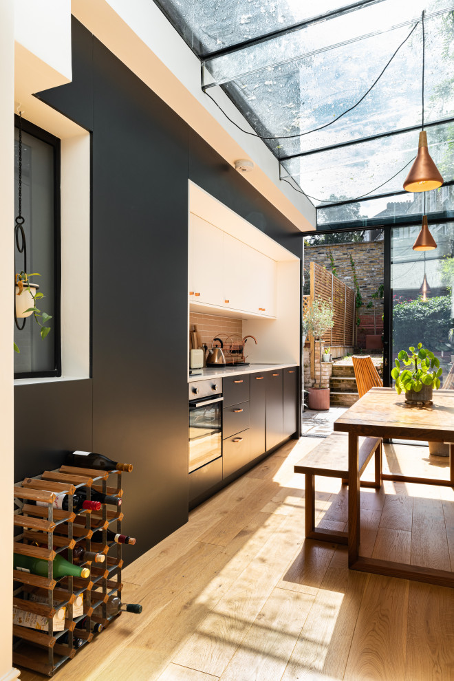 Moderne Wohnküche ohne Insel mit weißer Arbeitsplatte in London