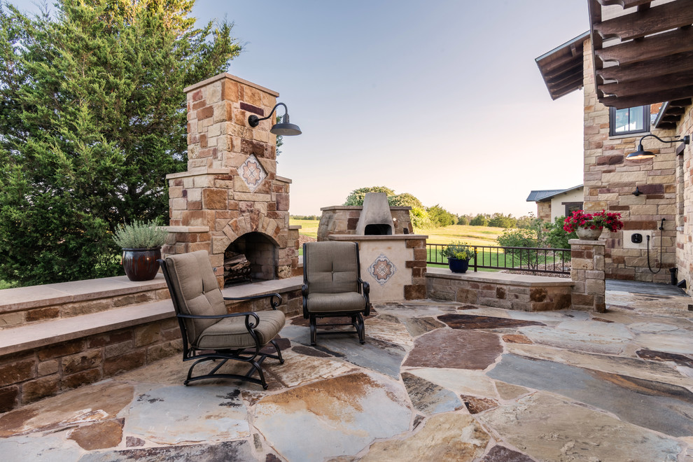 Expansive mediterranean courtyard patio in Austin with an outdoor kitchen, a pergola and natural stone pavers.