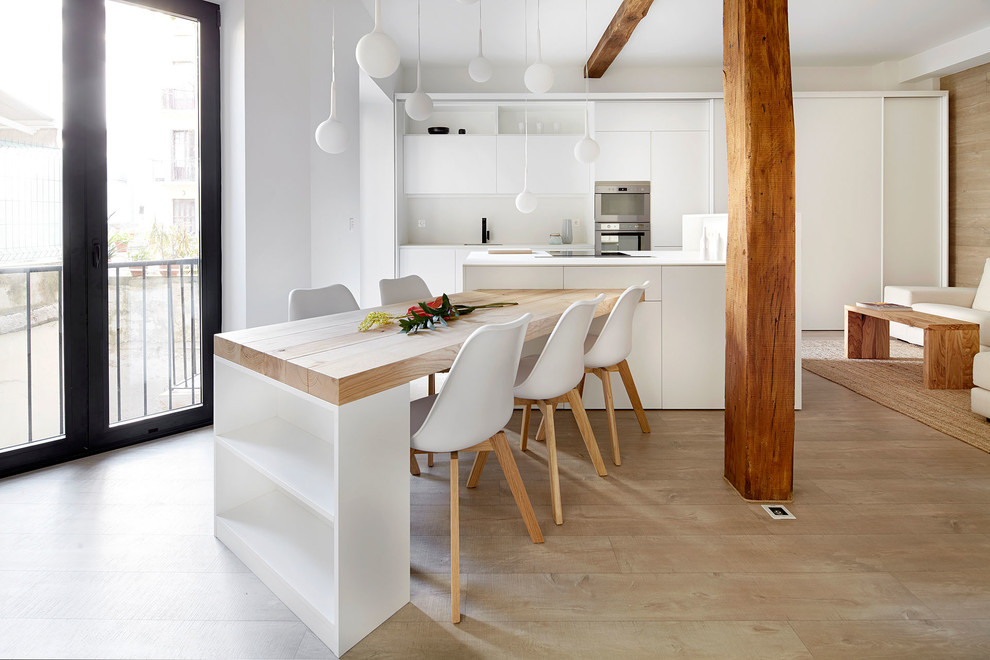 Contemporary open plan kitchen in Other with a single-bowl sink, flat-panel cabinets, white cabinets, white splashback, stainless steel appliances, light hardwood floors, multiple islands, beige floor and white benchtop.