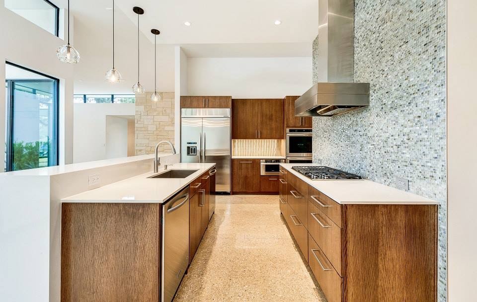 This is an example of a large modern galley kitchen in Dallas with an undermount sink, beaded inset cabinets, quartz benchtops, blue splashback, glass tile splashback, stainless steel appliances and concrete floors.