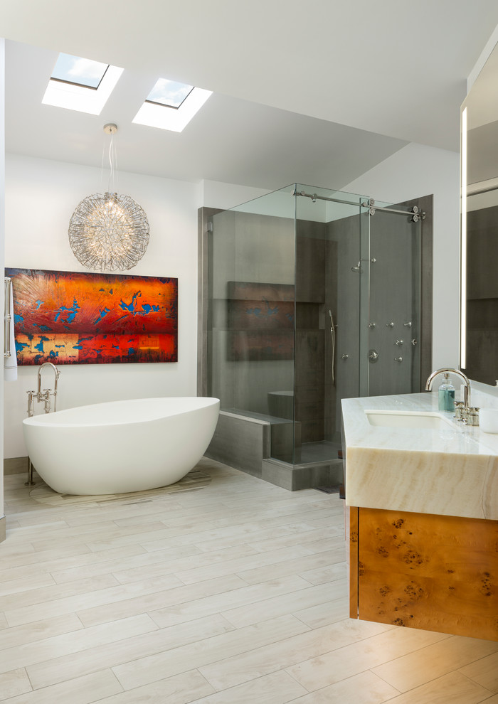 Inspiration for a large contemporary master bathroom in Other with flat-panel cabinets, light wood cabinets, a freestanding tub, a corner shower, gray tile, porcelain tile, white walls, porcelain floors, an undermount sink, onyx benchtops, beige floor, a sliding shower screen and white benchtops.