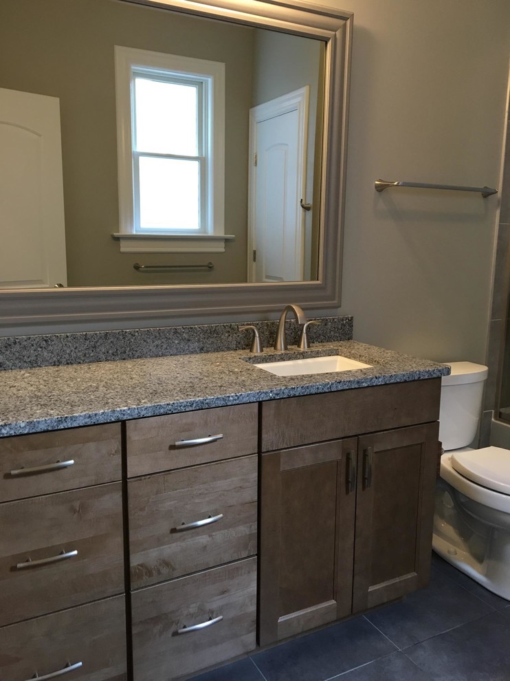 Inspiration for a mid-sized transitional kids bathroom in DC Metro with shaker cabinets, medium wood cabinets, an alcove tub, a shower/bathtub combo, a two-piece toilet, beige tile, gray tile, stone tile, grey walls, slate floors, an undermount sink and granite benchtops.