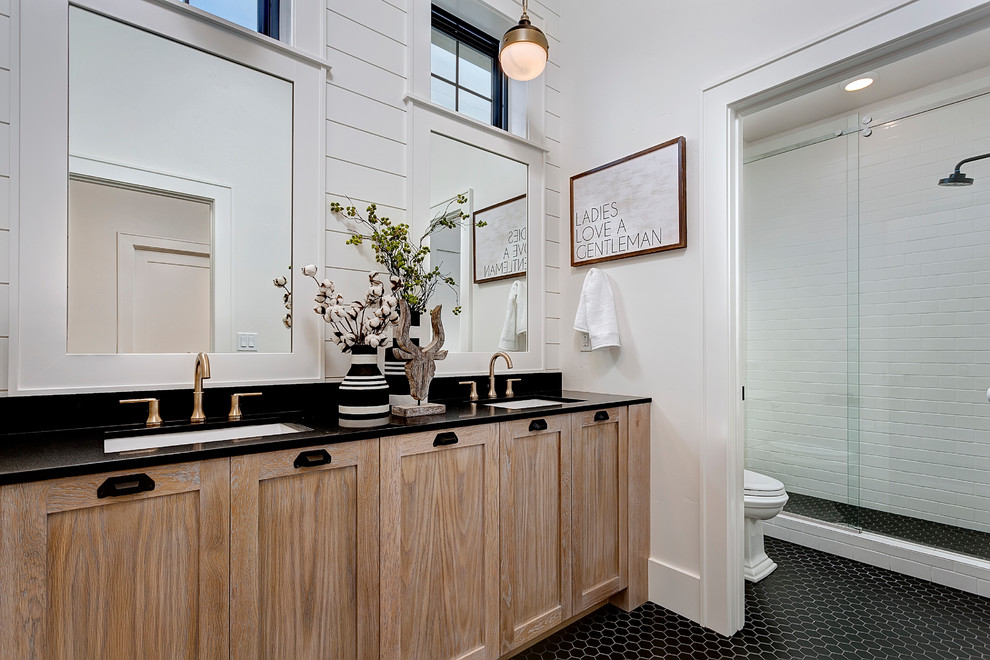 Photo of a country bathroom in Los Angeles with engineered quartz benchtops, shaker cabinets, medium wood cabinets, white tile, subway tile, white walls, mosaic tile floors, an undermount sink, black floor and a sliding shower screen.
