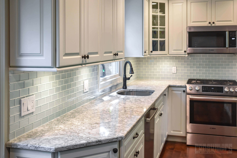 Inspiration for a mid-sized l-shaped eat-in kitchen in New York with an undermount sink, raised-panel cabinets, white cabinets, quartz benchtops, grey splashback, glass tile splashback, stainless steel appliances, plywood floors, with island and brown floor.