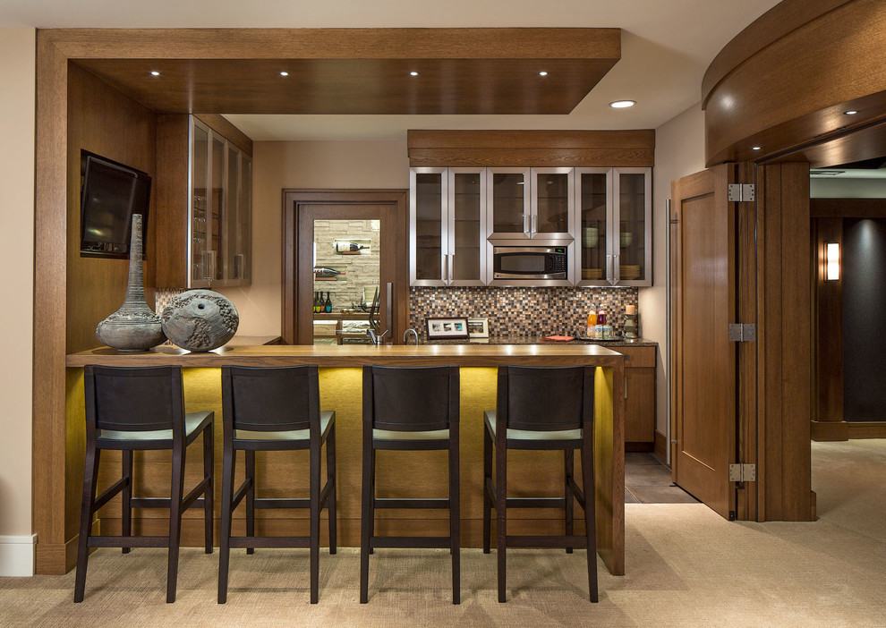 Photo of a transitional u-shaped seated home bar in Omaha with an undermount sink, flat-panel cabinets, medium wood cabinets, granite benchtops, multi-coloured splashback, mosaic tile splashback and ceramic floors.