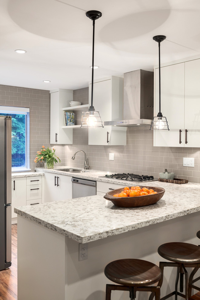 Inspiration for a mid-sized transitional l-shaped open plan kitchen in Vancouver with flat-panel cabinets, white cabinets, grey splashback, subway tile splashback, stainless steel appliances, quartz benchtops, medium hardwood floors, a double-bowl sink and no island.