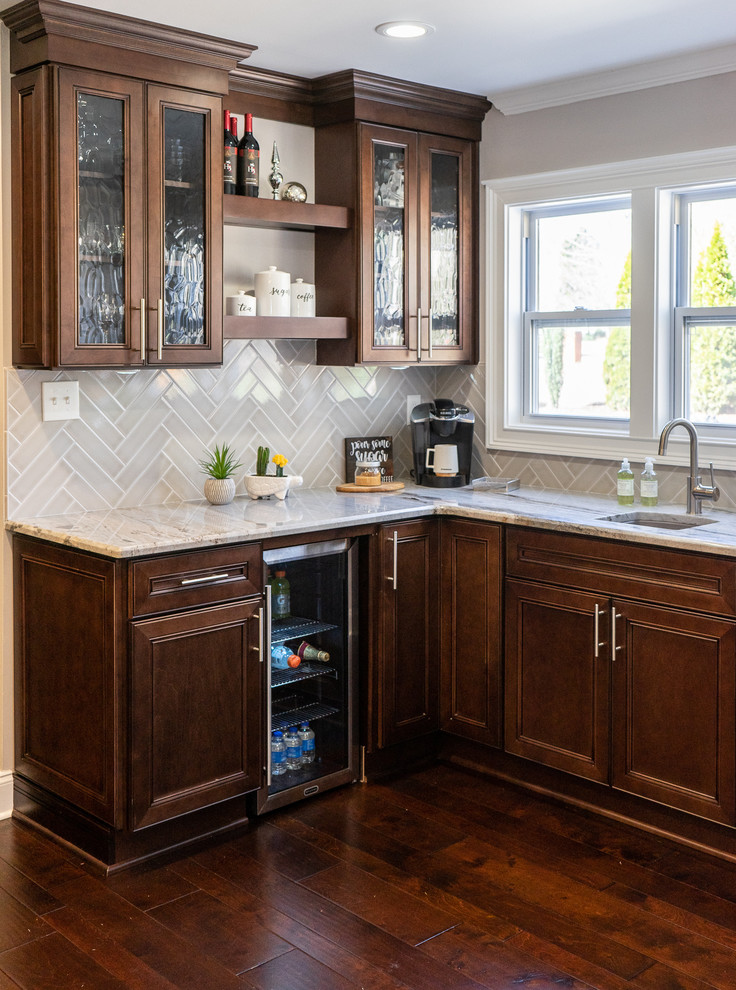 Photo of a mid-sized transitional eat-in kitchen in Atlanta with an undermount sink, shaker cabinets, brown cabinets, granite benchtops, grey splashback, subway tile splashback, black appliances, dark hardwood floors, with island, brown floor and multi-coloured benchtop.