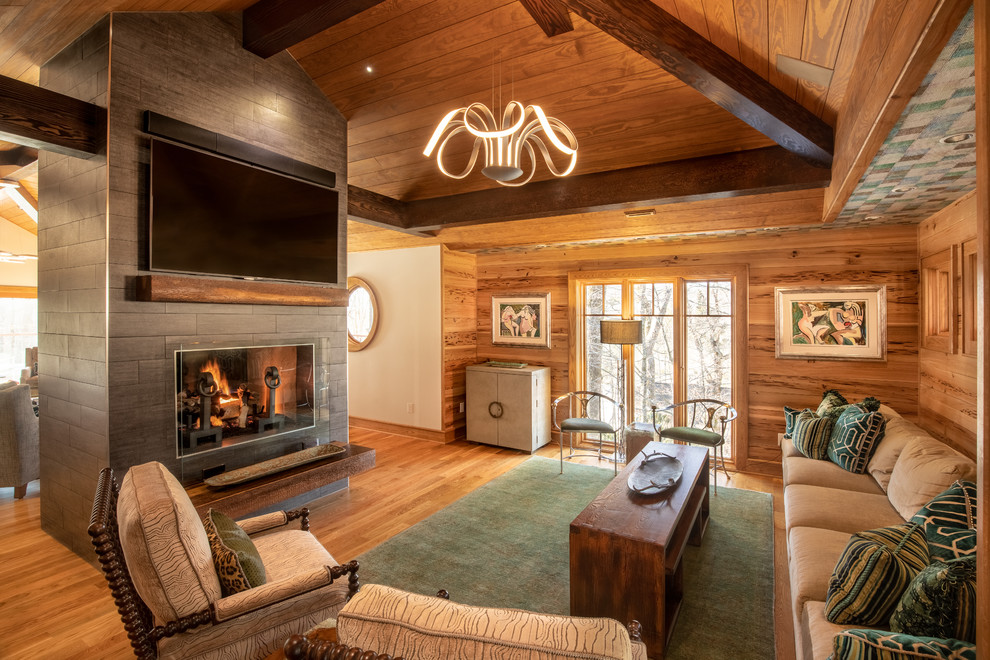 This is an example of a country open concept living room in Charlotte with brown walls, medium hardwood floors, a standard fireplace, a tile fireplace surround and brown floor.