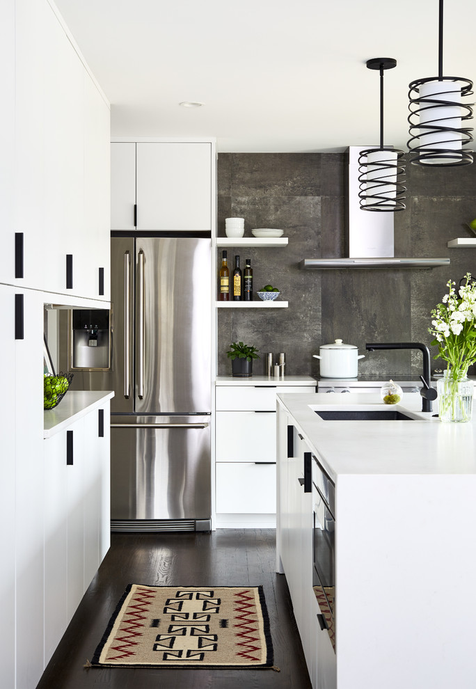 Small contemporary l-shaped separate kitchen in DC Metro with an undermount sink, flat-panel cabinets, white cabinets, quartz benchtops, grey splashback, porcelain splashback, stainless steel appliances, dark hardwood floors, with island and white benchtop.