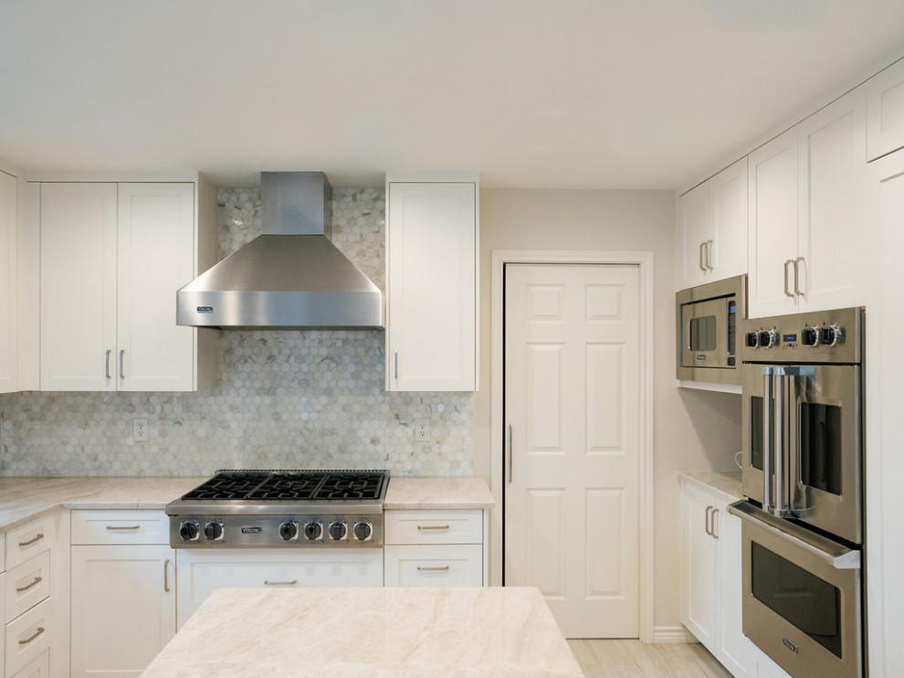 Example of a large transitional u-shaped medium tone wood floor and brown floor enclosed kitchen design in Dallas with an undermount sink, raised-panel cabinets, beige cabinets, quartzite countertops, white backsplash, marble backsplash, stainless steel appliances, an island and beige countertops
