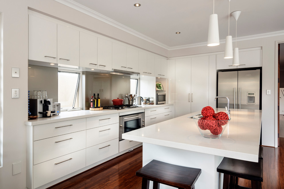 Inspiration for a contemporary l-shaped kitchen in Perth with flat-panel cabinets, white cabinets, grey splashback, glass sheet splashback, stainless steel appliances, medium hardwood floors and with island.