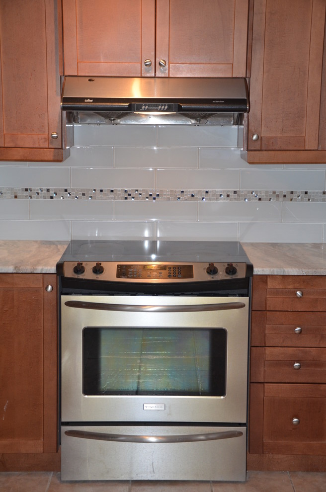 Inspiration for a small transitional u-shaped enclosed kitchen remodel in Toronto with beaded inset cabinets, medium tone wood cabinets, granite countertops, white backsplash, glass tile backsplash, stainless steel appliances and no island