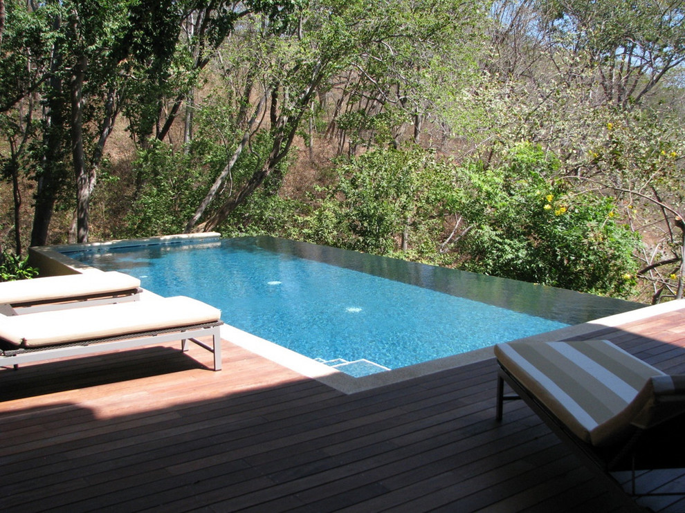 Photo of a mid-sized contemporary rectangular infinity pool in Other with decking.