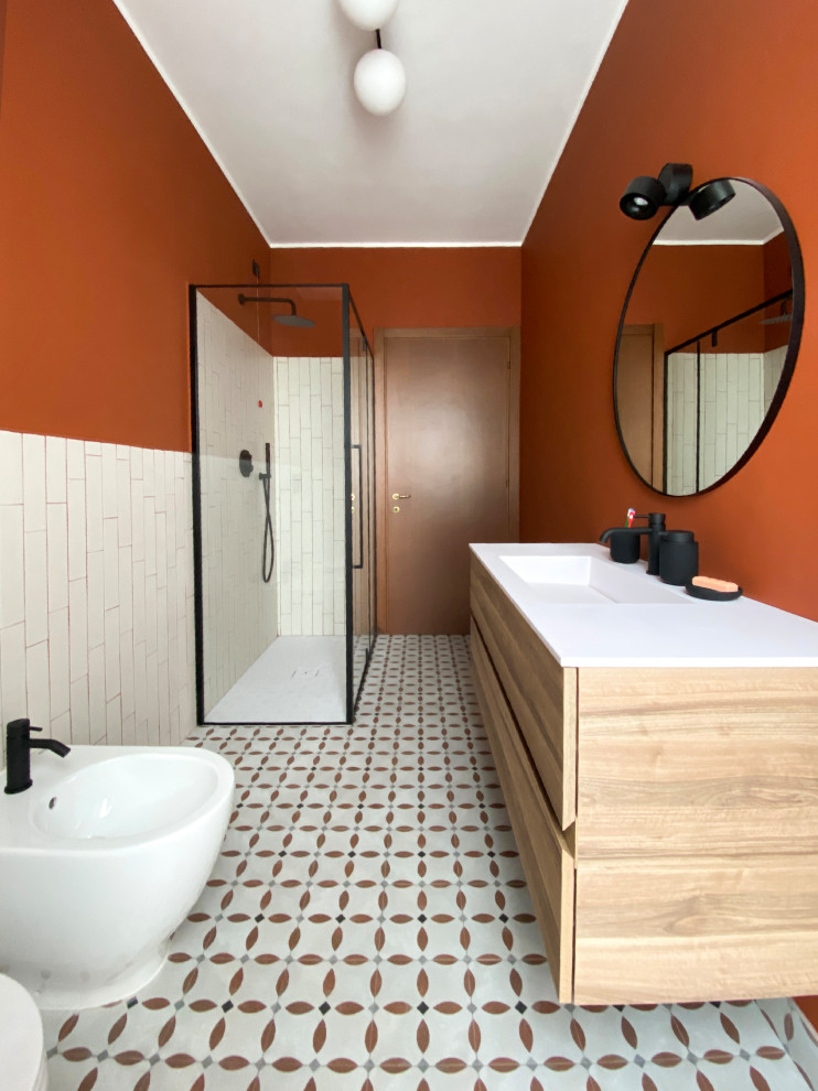 Idéer för att renovera ett litet funkis vit vitt badrum med dusch, med släta luckor, skåp i ljust trä, en kantlös dusch, en bidé, vit kakel, keramikplattor, röda väggar, cementgolv, ett integrerad handfat, bänkskiva i kvarts, flerfärgat golv och dusch med gångjärnsdörr