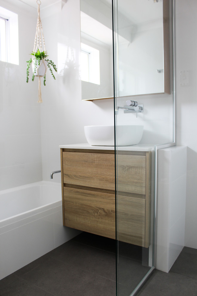 Photo of a small modern kids bathroom in Perth with flat-panel cabinets, dark wood cabinets, a drop-in tub, a corner shower, white tile, ceramic tile, white walls, porcelain floors, a vessel sink, engineered quartz benchtops, grey floor, a hinged shower door and white benchtops.