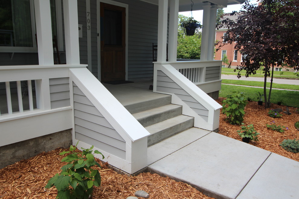 Mid-sized traditional front yard verandah in Other with concrete pavers and a roof extension.